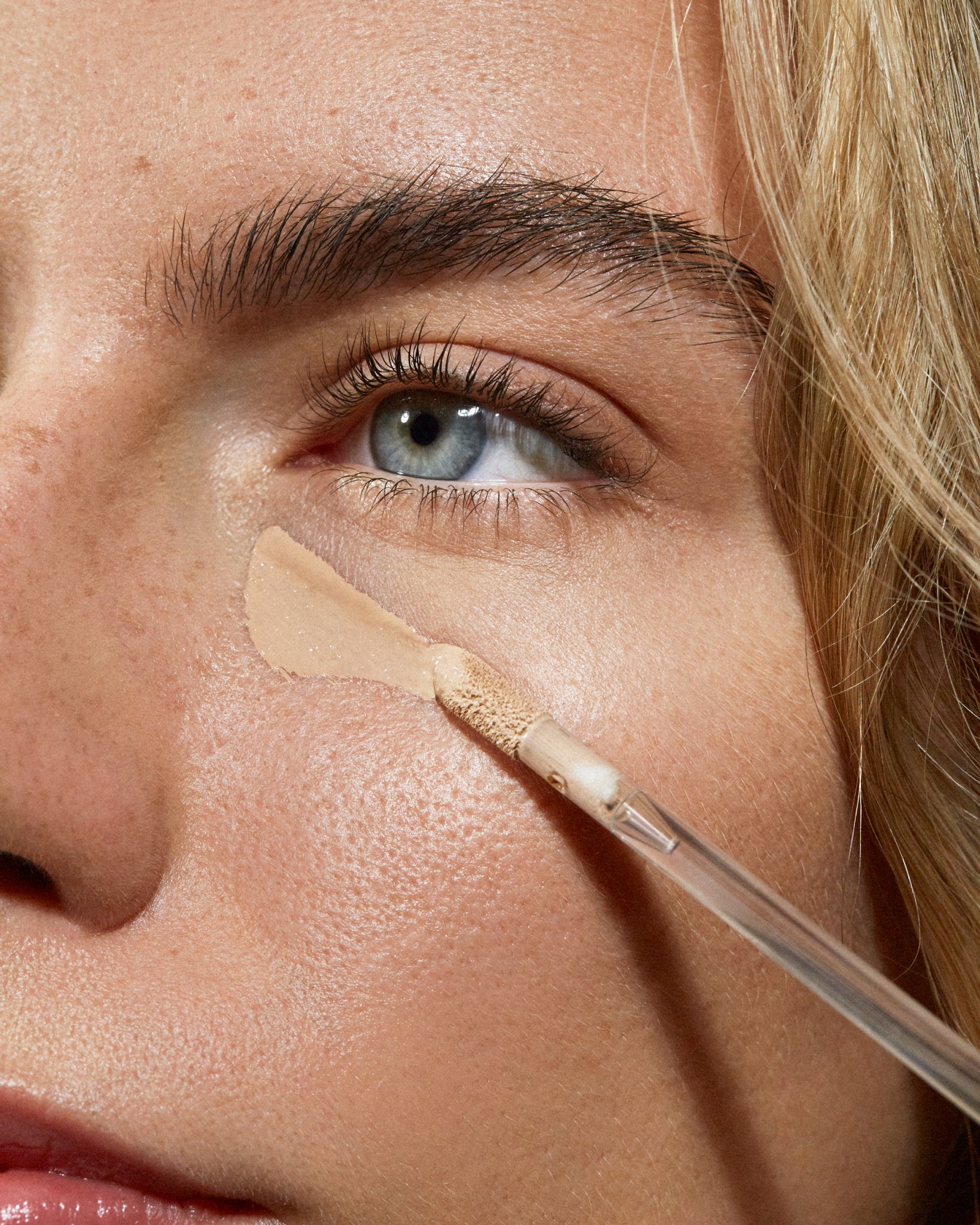 Model wearing MÁDARA Organic Skincare the concealer sand on A6109 concealer on skin; close-up portrait shows natural application results.
